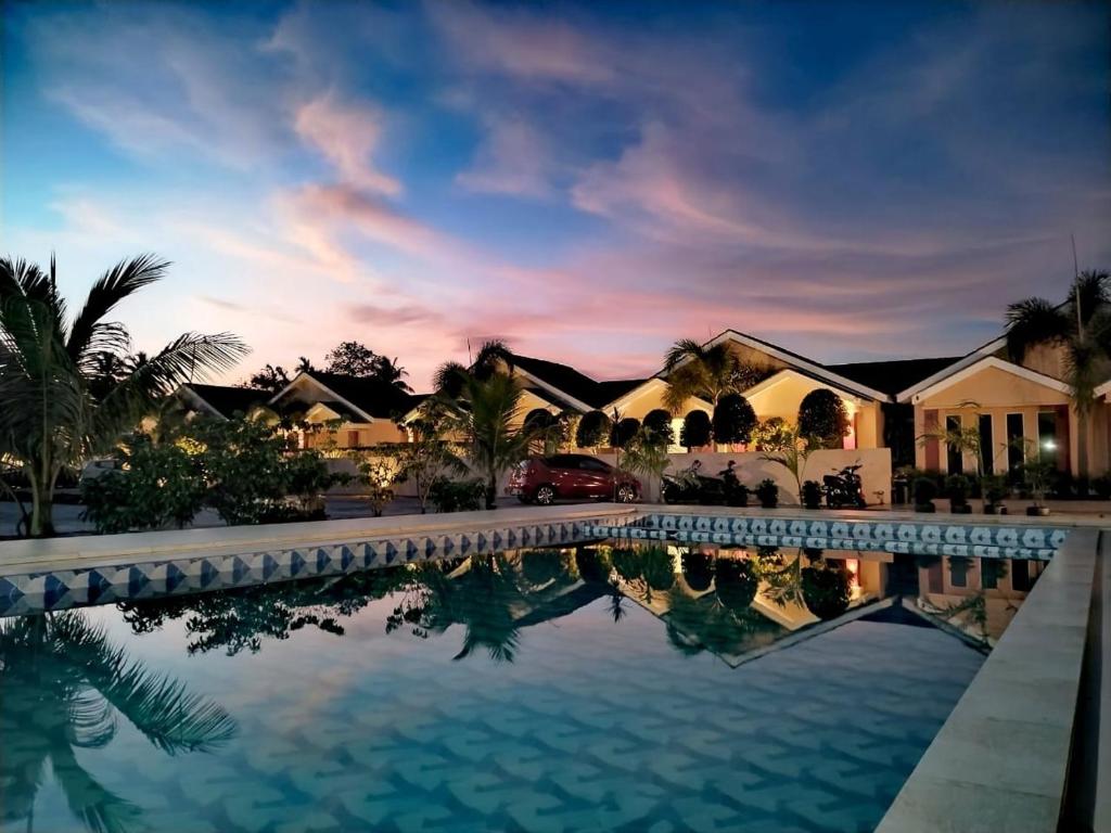a villa with a swimming pool at dusk at Nahdhoh Langkawi Resort in Pantai Cenang