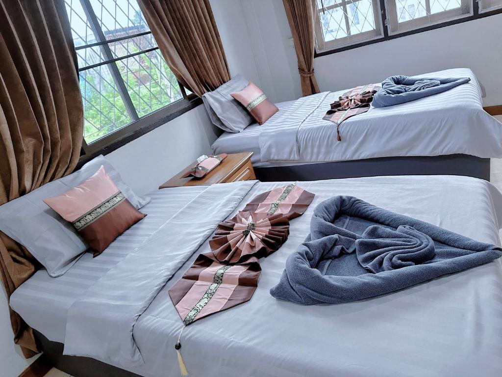 a room with two beds with towels on them at Guesthouse Chubu เกสต์เฮ้าส์ชูบู in Chiang Mai