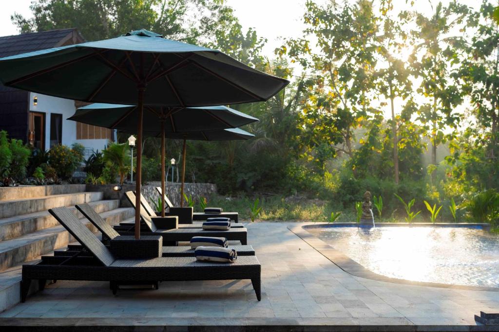 a row of lounge chairs with an umbrella next to a pool at Jewel of Penida in Nusa Penida
