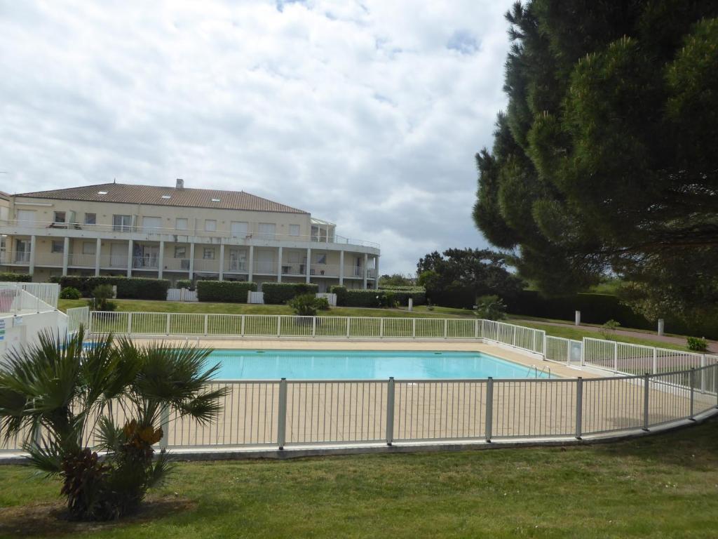 une clôture autour d'une piscine en face d'un bâtiment dans l'établissement Appartement Cosy avec Piscine, près du Lac de Tanchet et Plages, Les Sables-d'Olonne - FR-1-325-129, à Les Sables-dʼOlonne