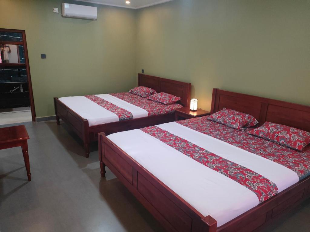 una camera con due letti con lenzuola rosse e bianche di Mango Guesthouse a Pangandaran
