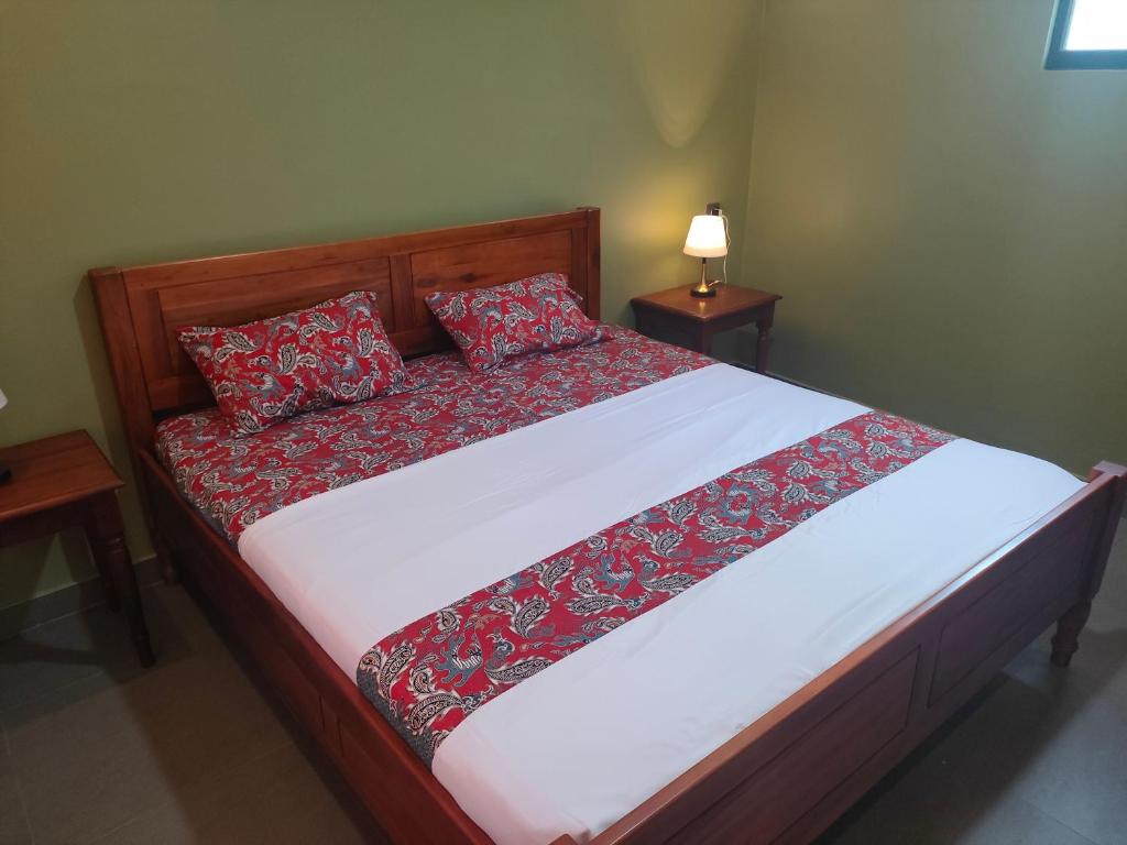 un letto con cuscini rossi sopra in una camera da letto di Mango Guesthouse a Pangandaran