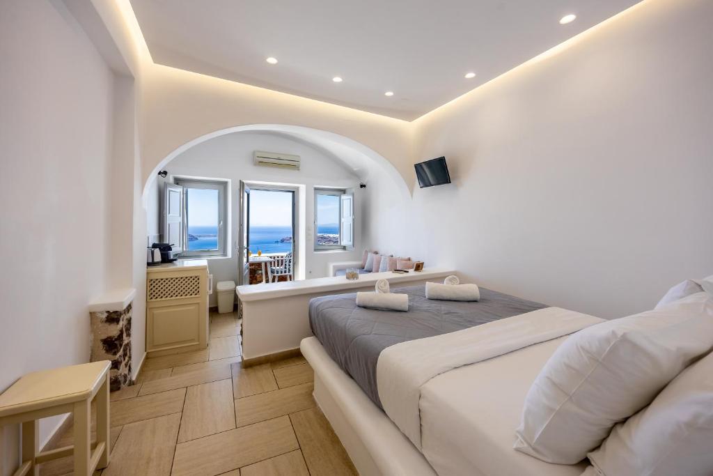 Un dormitorio blanco con una cama grande y una mesa en Ilioperato Hotel, en Imerovigli