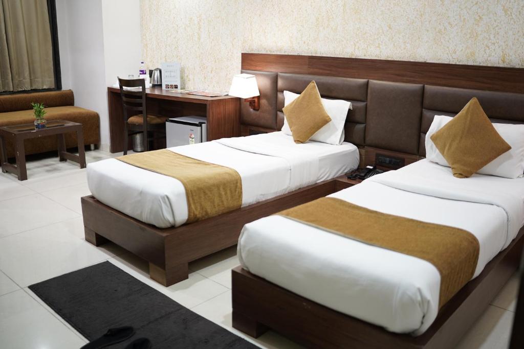 a hotel room with two beds and a desk at Hotel LA PEARL, Bhopal in Bhopal