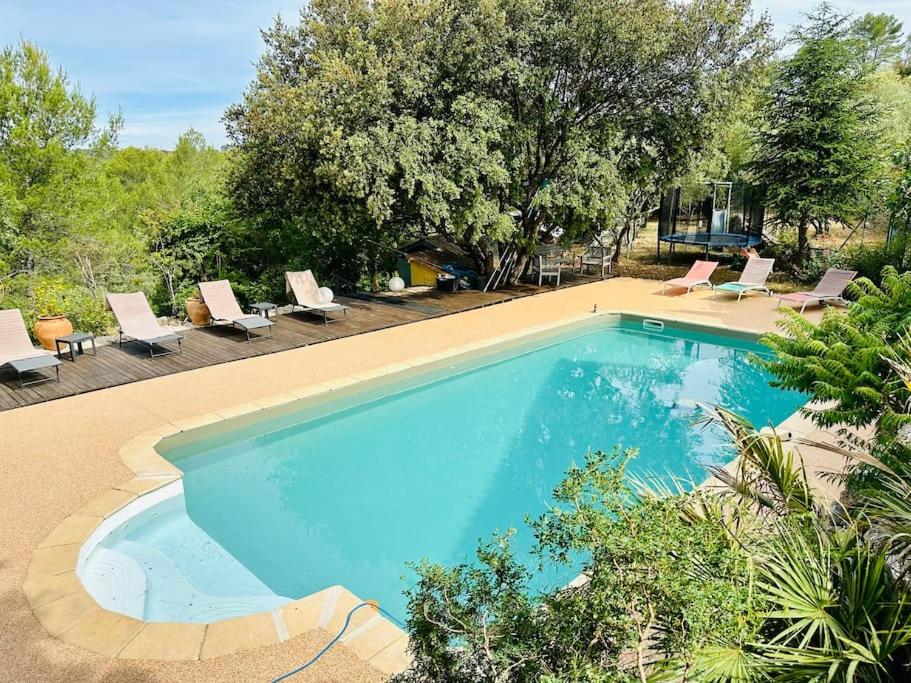 une grande piscine bleue avec des chaises longues et des arbres dans l'établissement Villa Les Ruches - Piscine & Clim, à Bras