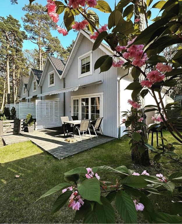 a white house with a table and chairs and flowers at 8 Sosen Pobierowo in Pobierowo