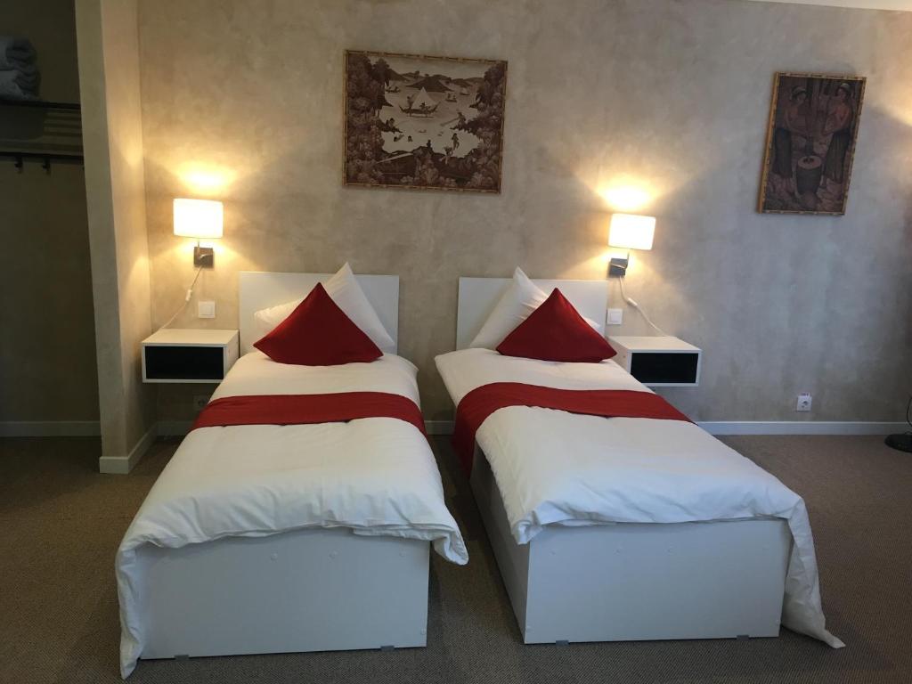 two beds in a hotel room with red pillows at Csiki Hotel in Miercurea-Ciuc