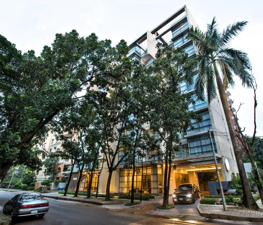 ダッカにあるSpace Hotel and Apartmentsの通りの前にヤシの木が茂る建物