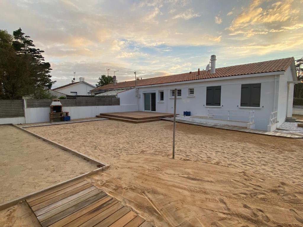 ein weißes Haus mit einem sandigen Hof davor in der Unterkunft Maison 6 pers - 3ch à Saint Hilaire de riez classé 3 Etoiles in Saint-Hilaire-de-Riez