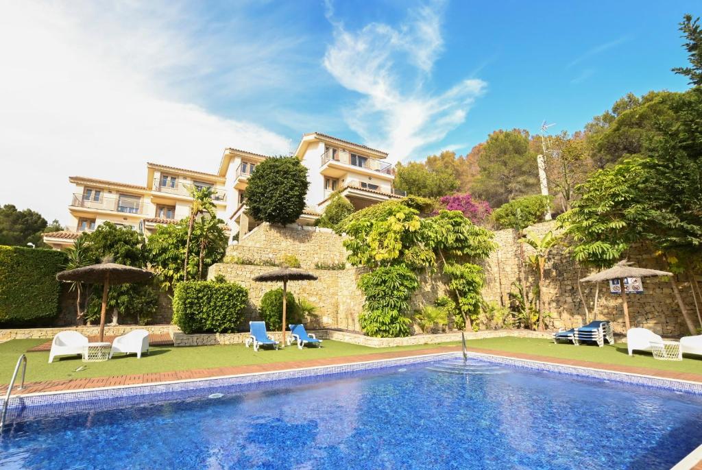 a swimming pool with chairs and umbrellas in front of a house at Villa Alegre Playa Calpe Grupo Terra de Mar, alojamientos con encanto in Calpe