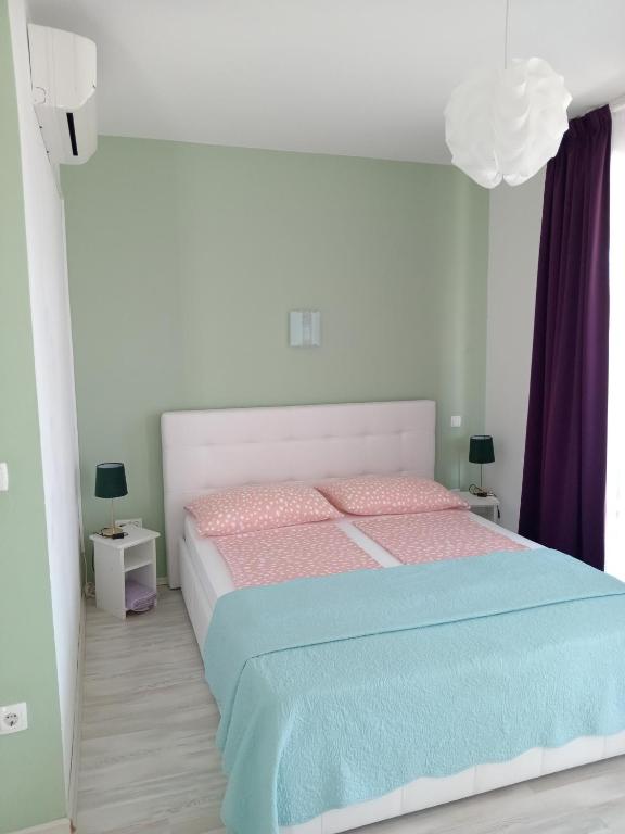 a bedroom with a bed with pink and blue sheets at Ana Rooms in Krk