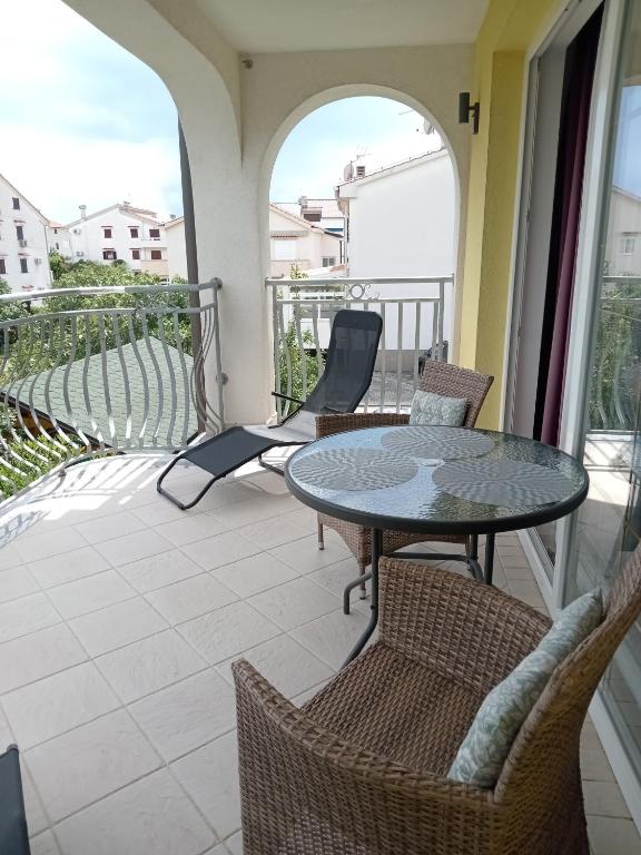 a patio with two tables and chairs on a balcony at Ana Rooms in Krk