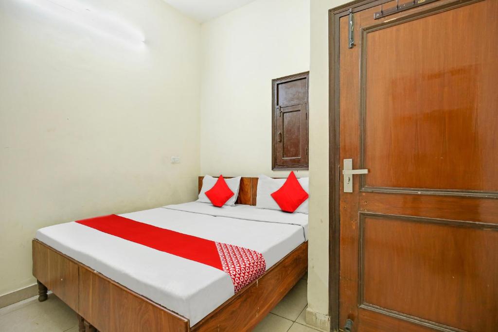 um quarto com uma cama com almofadas vermelhas e uma porta em Wave Inn Guest House em Ludhiana
