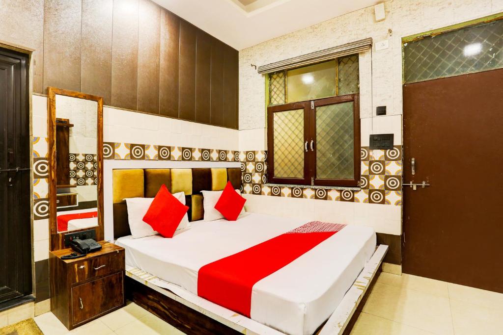 a bedroom with a large bed with red pillows at Flagship Royal Hotel in Kānpur
