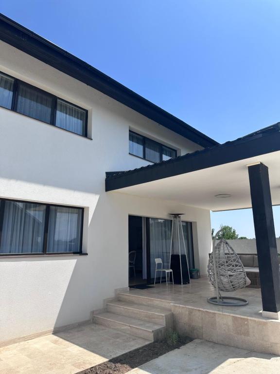 Dieses weiße Haus verfügt über eine Terrasse mit einem Stuhl. in der Unterkunft Vila Meditteran in Turbaţi