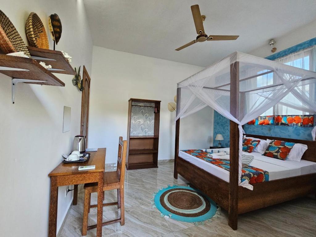 a bedroom with a desk and a bed with a canopy at Zanzicrown in Nungwi