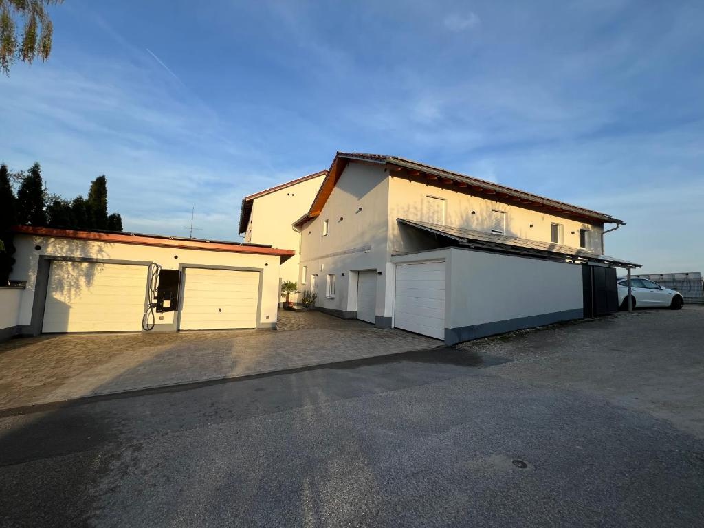 un edificio bianco con due porte da garage e un'auto di Ferienwohnung Villa Bachfischer a Viehhausen