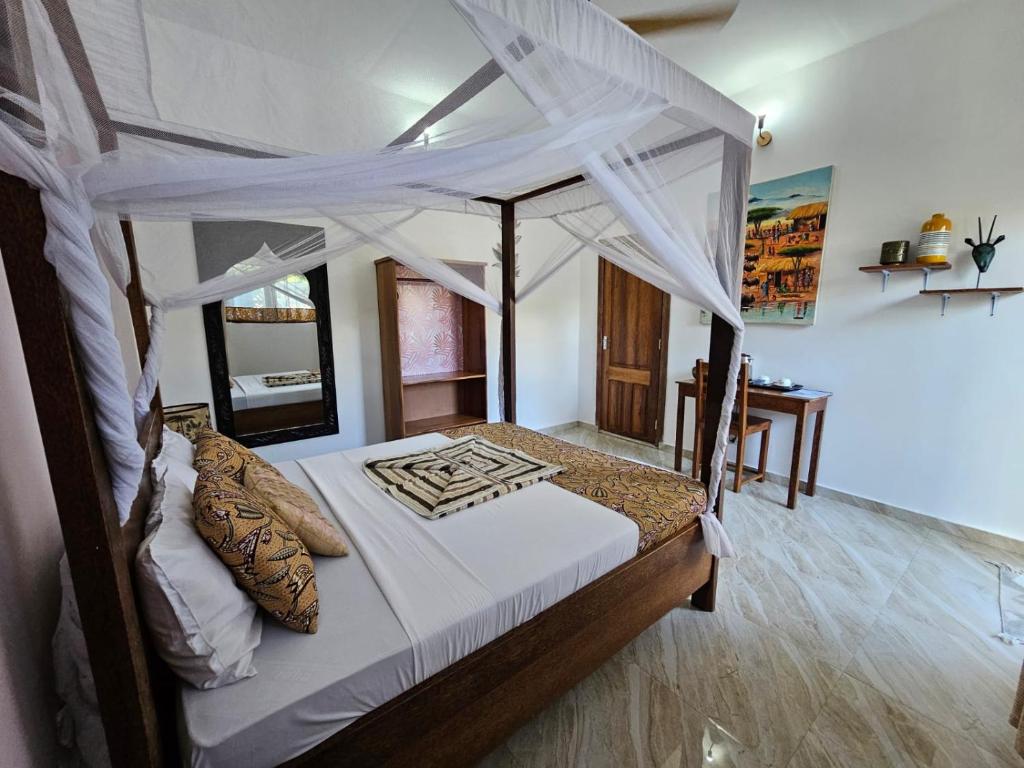 a bedroom with a canopy bed and a desk at Zanzicrown in Nungwi