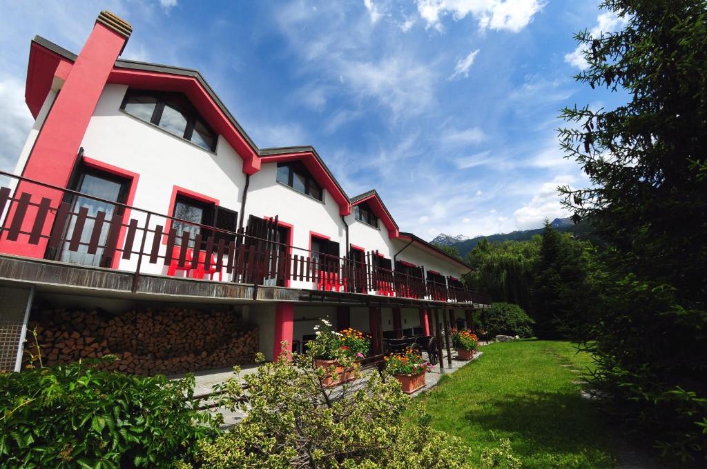 a building with red and white trim and a yard at Residence Eden Park in Aosta