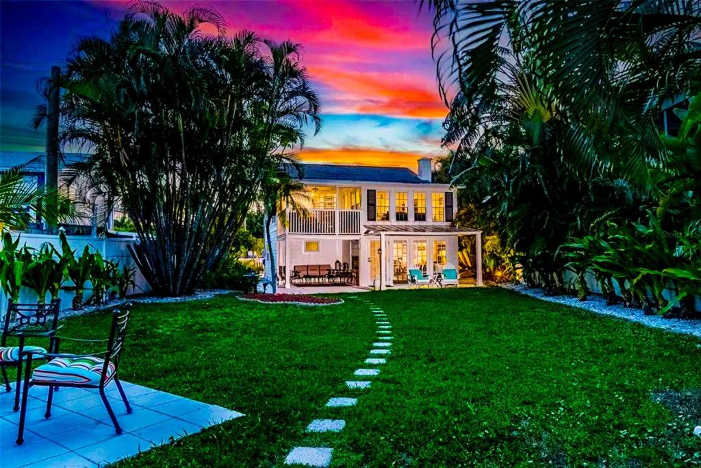 a house with a lawn with a chair and palm trees at Seaside Serenity in Bradenton Beach