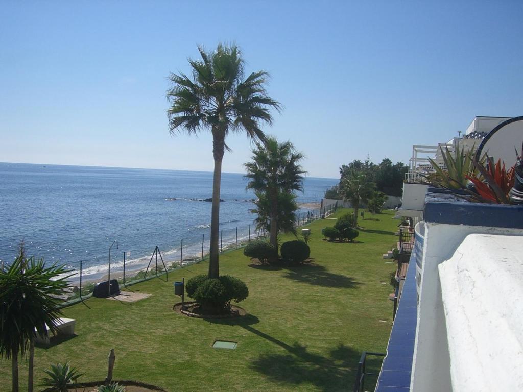 a view of the ocean from a balcony with a palm tree at APT EL FARO ARKADIA BEACH MIJAS COSTA Marvellous Frontbeach with stunning seaviews and historic lighthouse in Mijas Costa