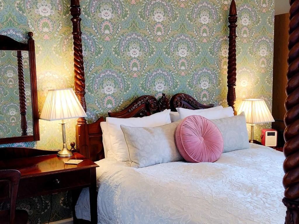 ein Schlafzimmer mit einem Bett mit einem rosa Kissen darauf in der Unterkunft Chough's Nest Hotel in Lynton