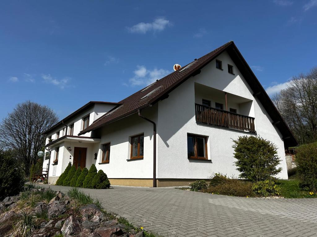 a white house with a black roof and a driveway at Restaurace a penzion Na Stráni in Klášterec nad Orlicí