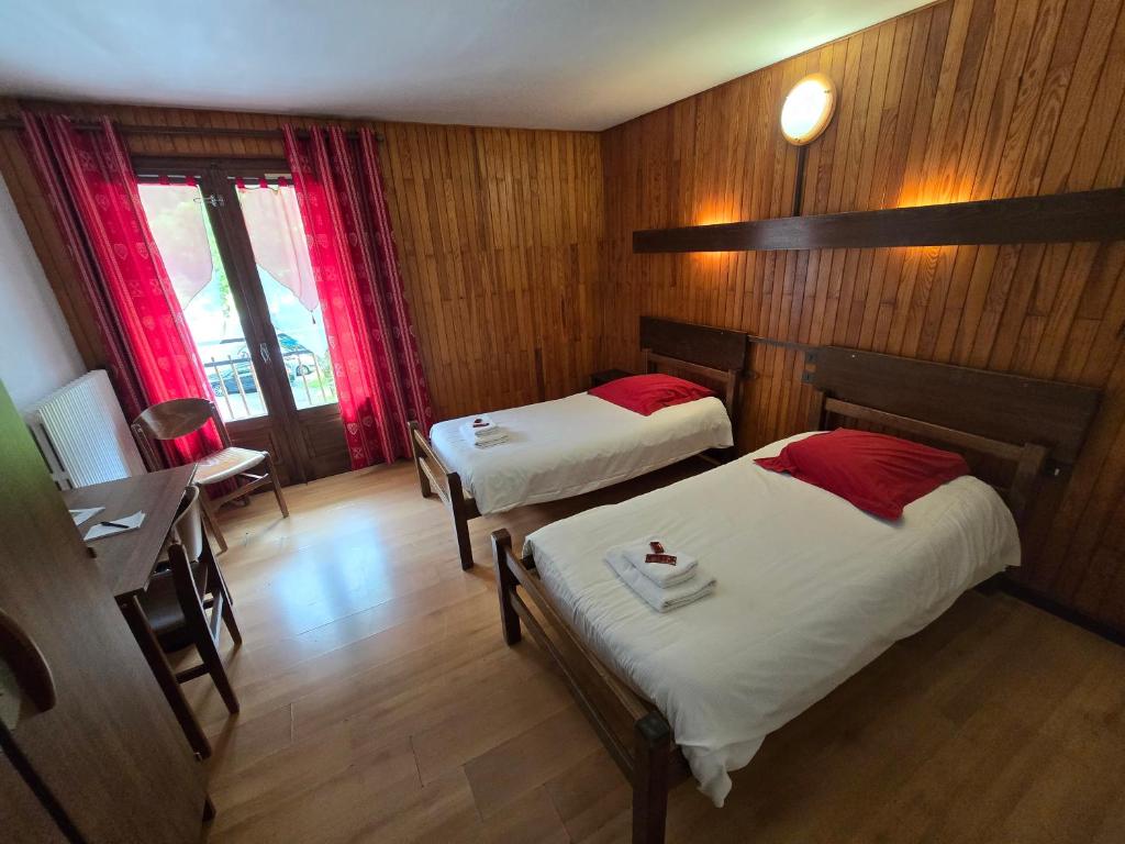 a room with two beds and a table and a desk at Hotel et centre de vacances Le Choucas in Sixt