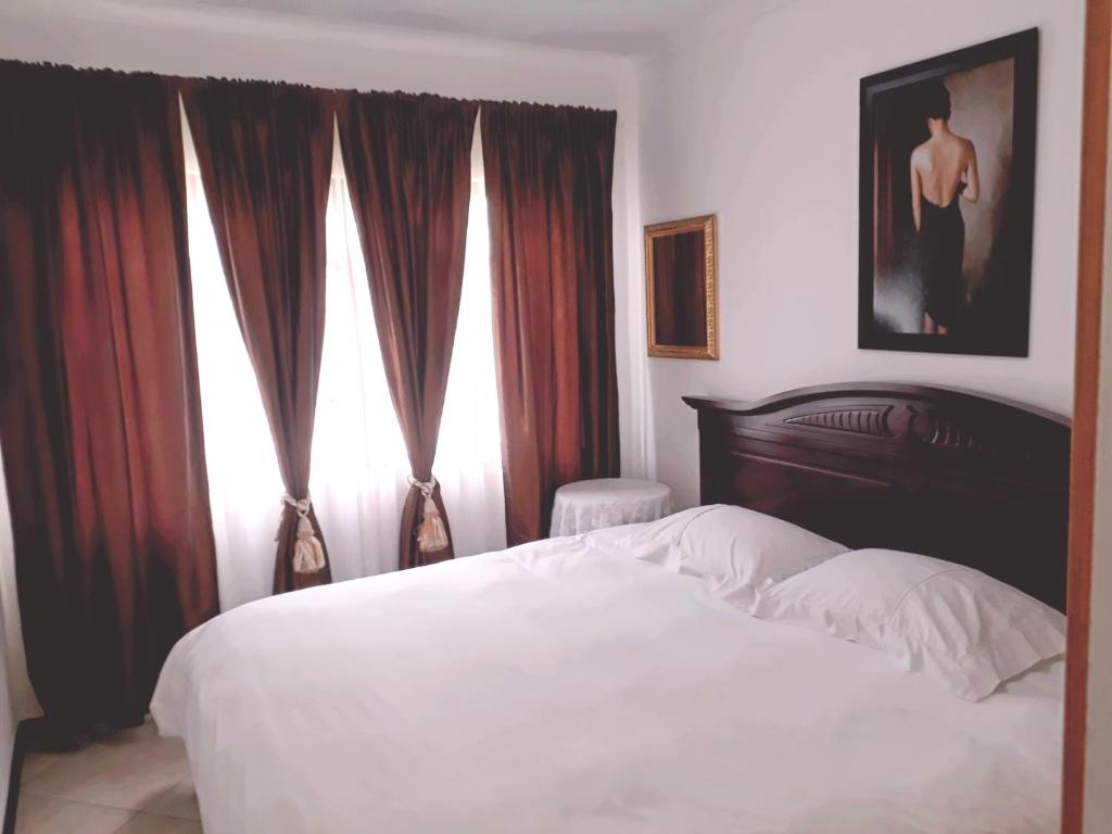 a bedroom with a white bed with red curtains at Mountain View Holiday Home in Franskraal
