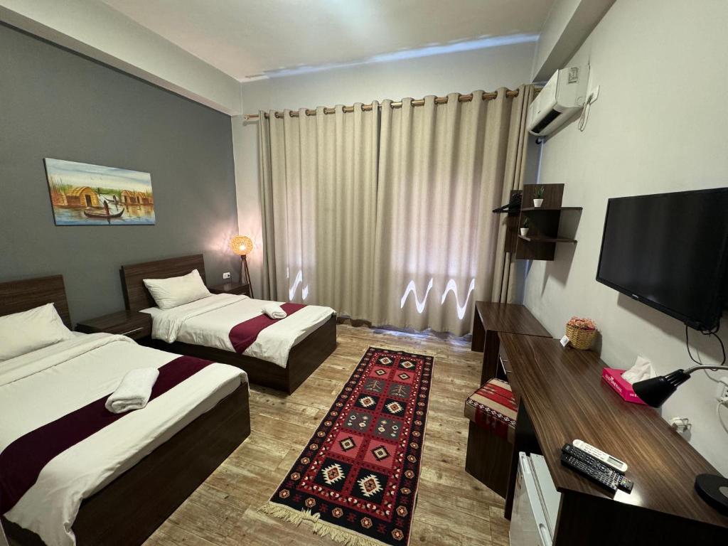 a hotel room with two beds and a flat screen tv at The Sydney Hotel in Amman
