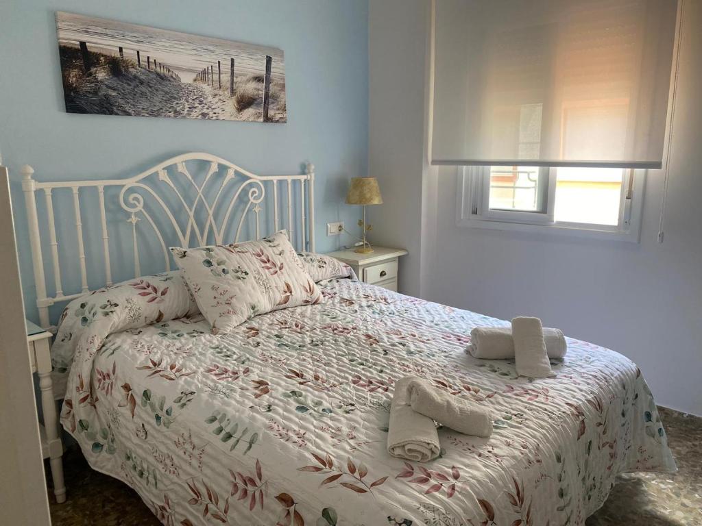 a bedroom with a white bed with slippers on it at Apartamento Centro Chipiona La Perla in Chipiona