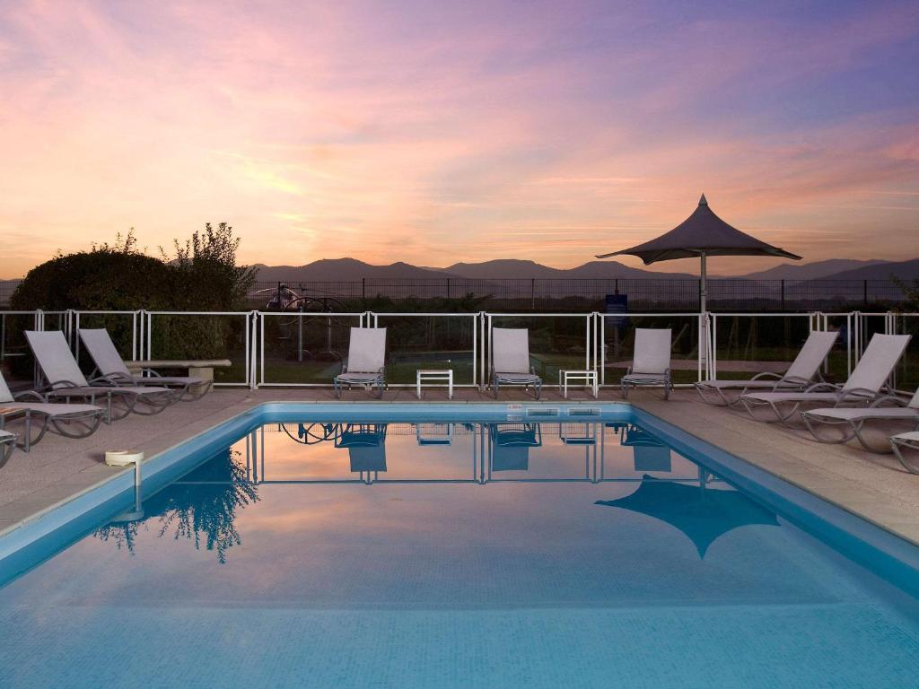 科爾馬的住宿－科爾馬北宜必思尚品酒店，一个带躺椅和遮阳伞的游泳池