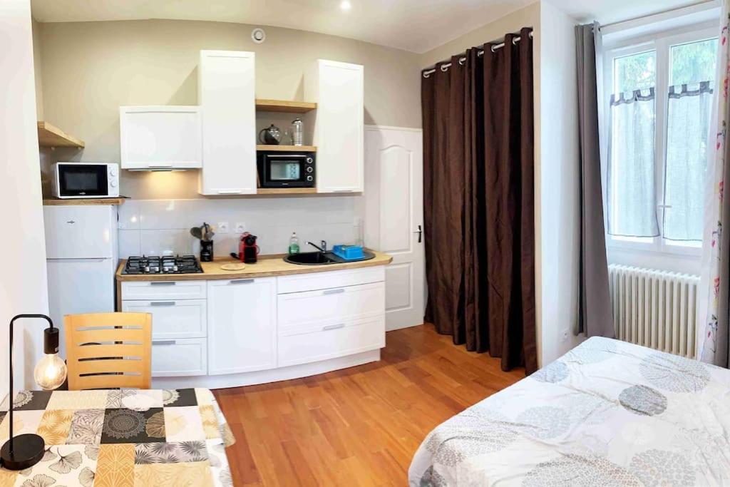 a kitchen with white cabinets and a bed in a room at Studio TOURNETTE in Chambéry