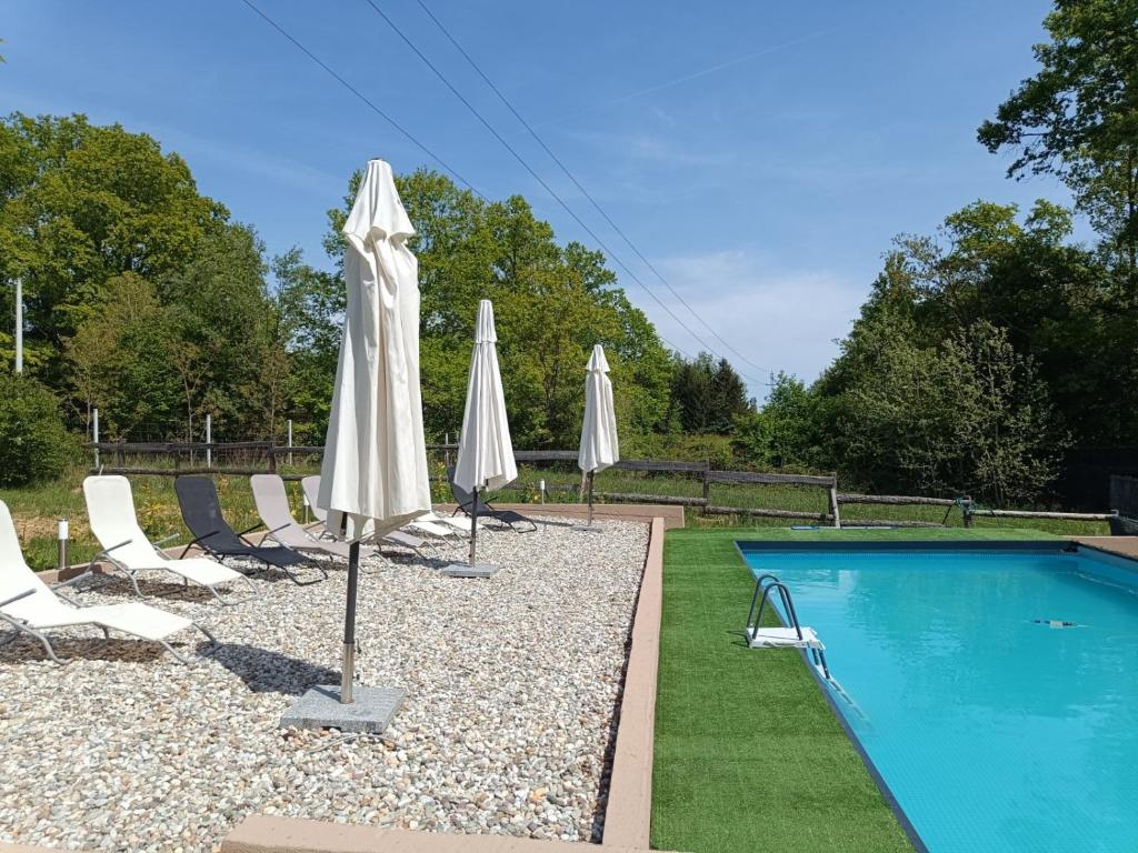 eine Gruppe von Sonnenschirmen und Stühlen neben einem Swimmingpool in der Unterkunft LAKE FISHING Resort in Lukinić Senovec