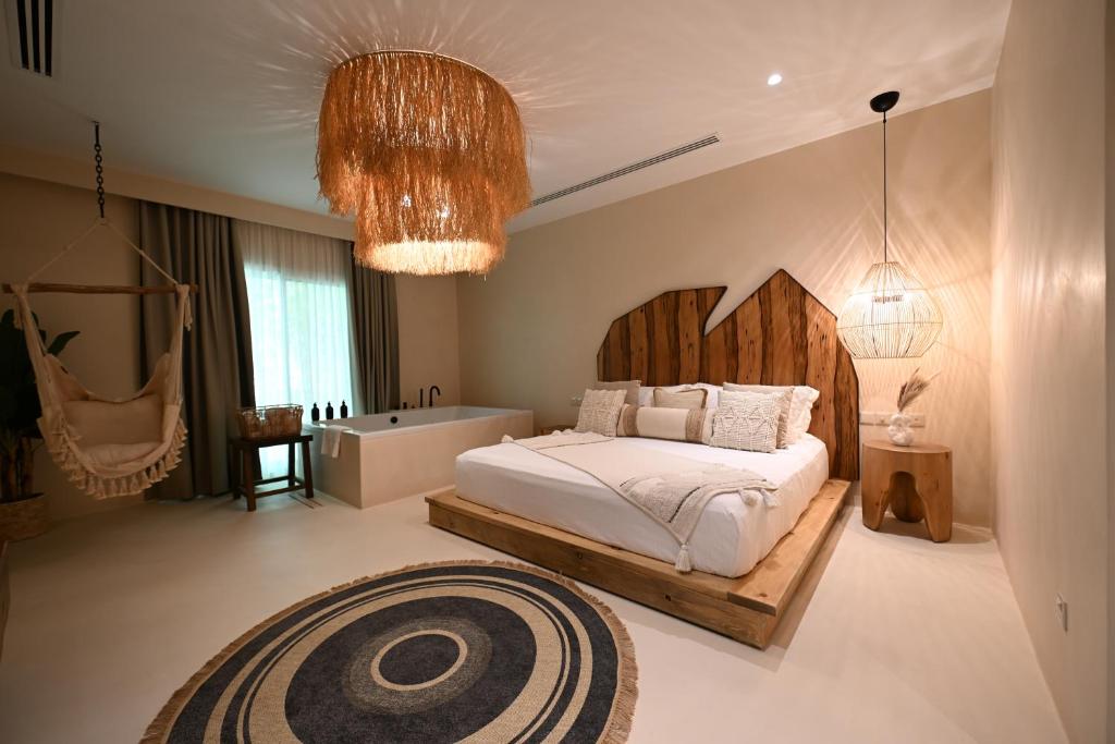 una camera con letto, vasca e lampadario a braccio di Umm Al Quwain Beach Hotel a Umm Al Quwain