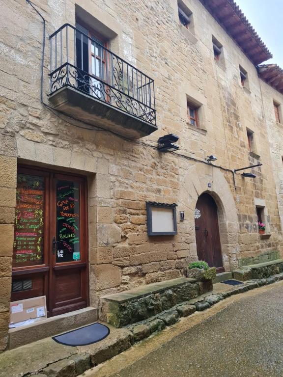 ウンカスティージョにあるBar Restaurante Albergue de Uncastilloの石造りの建物(バルコニー、ドア付)