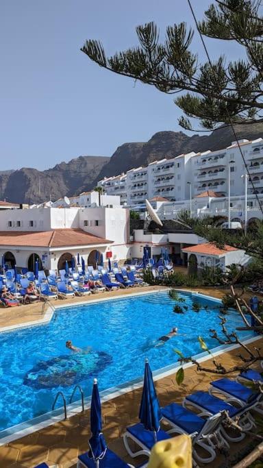 a swimming pool with chairs and people in a hotel at El Marques Resort Townhouse in Puerto de Santiago