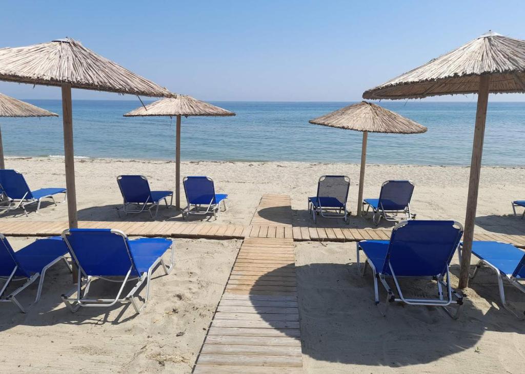 a group of chairs and umbrellas on the beach at Kastri Hotel in Néa Meságkala