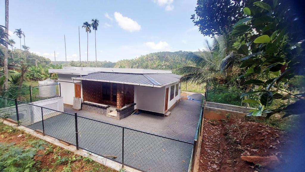 a small house in a field with a fence at Dream Nest Villa Wayanad in Kalpetta