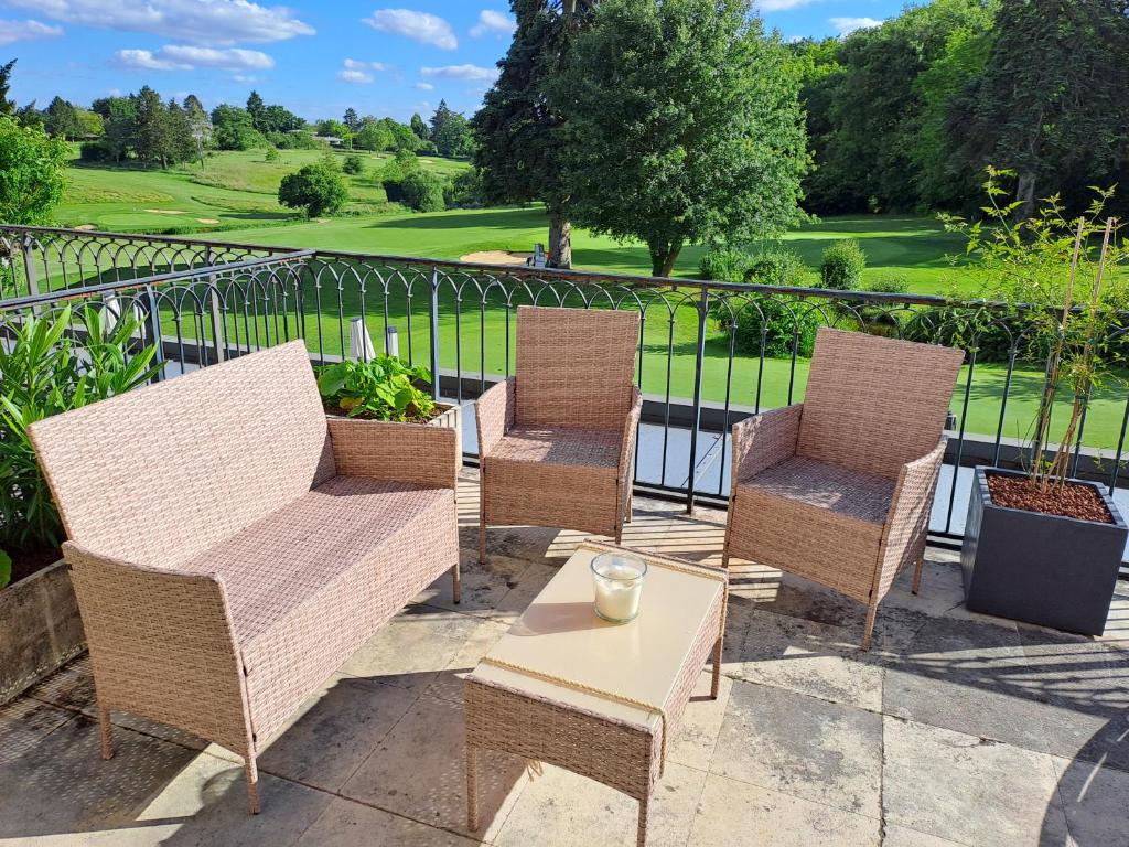 eine Gruppe von Stühlen und ein Tisch auf einer Terrasse in der Unterkunft Le Relais du Golf- Château de la Touche in Ballan-Miré