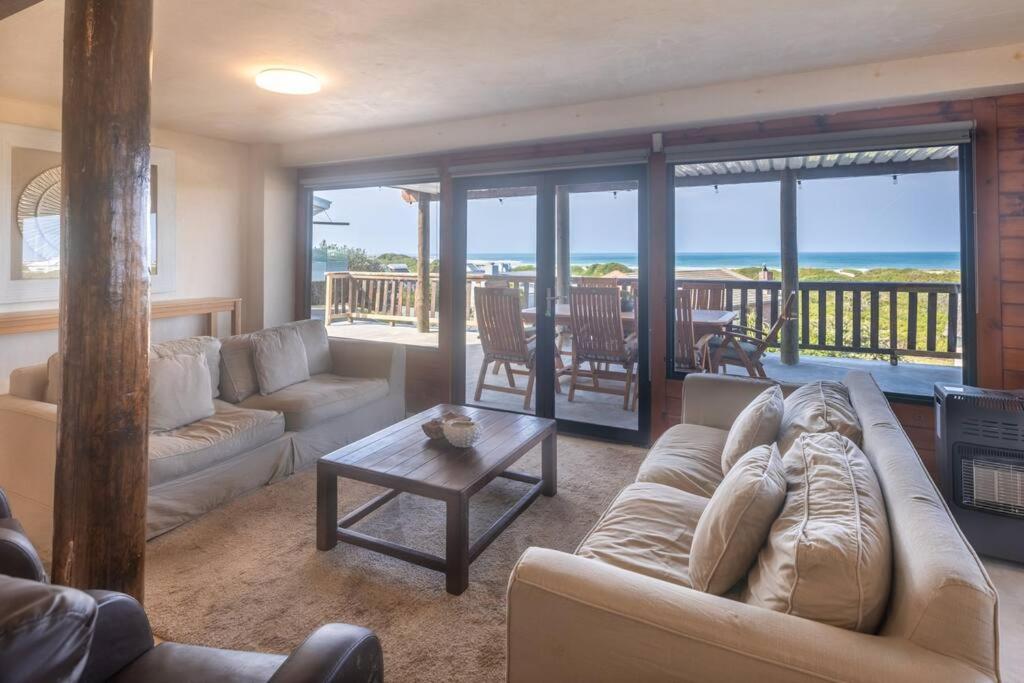 una sala de estar con un sofá y una mesa en Upmarket Sea View Apartment, en Cape St. Francis