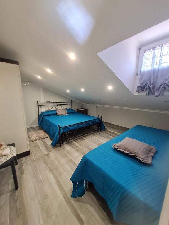 two beds in a room with blue sheets and a window at Villa Mattei Dreams in Rome