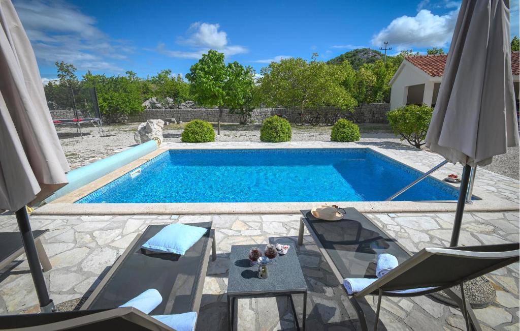 a pool with a table and chairs and an umbrella at Villa Silentio Dalmatia in Makarska