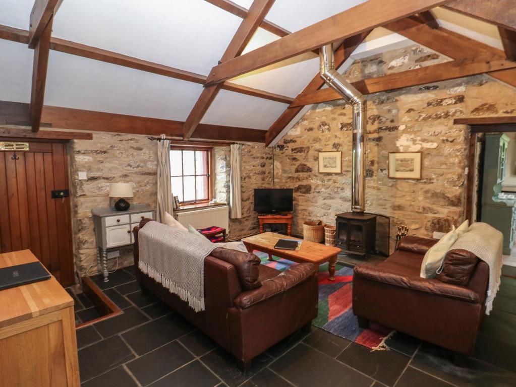 a living room with leather furniture and a stone wall at Preseli Hills Cottage in Fishguard