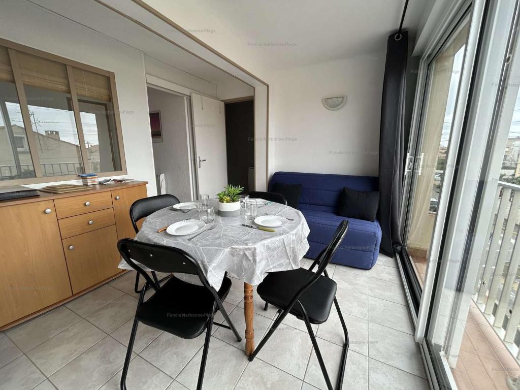 une table et des chaises dans une pièce avec un canapé bleu dans l'établissement Appartement rénové 2 pièces, 4 pers, à 150m de la mer - FR-1-229B-98, à Narbonne