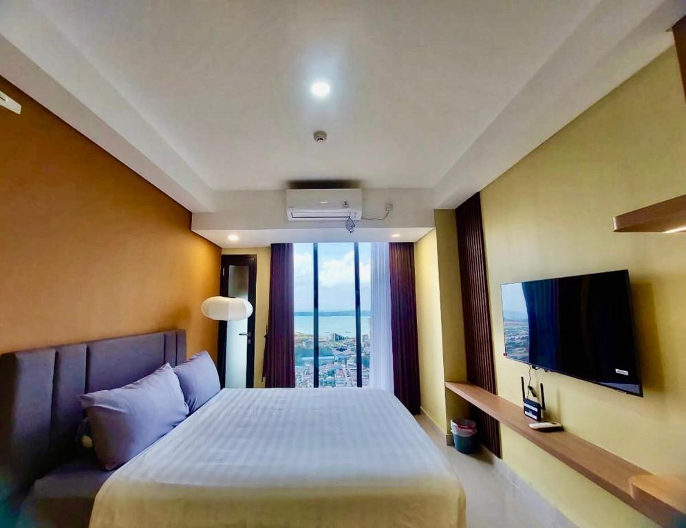 a bedroom with a large bed and a tv at Serene Studio Pollux Batam Center - High Floor Sea View in Batam Center
