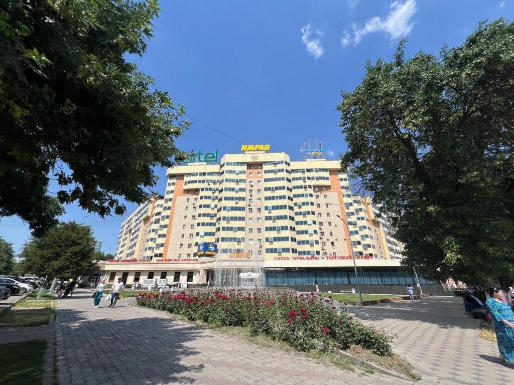 un grande edificio con dei fiori di fronte di Квартира 1 ком Тауке хана 33 a Shymkent