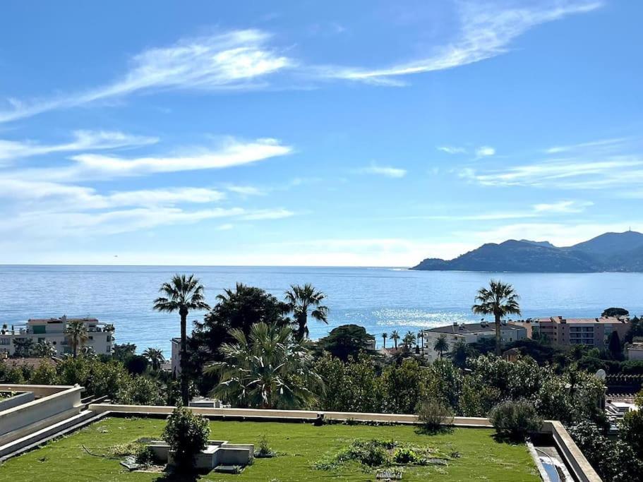 - une vue sur l'océan avec des palmiers et des bâtiments dans l'établissement Appartement haut de gamme vue mer classé 3 étoiles, à Cannes