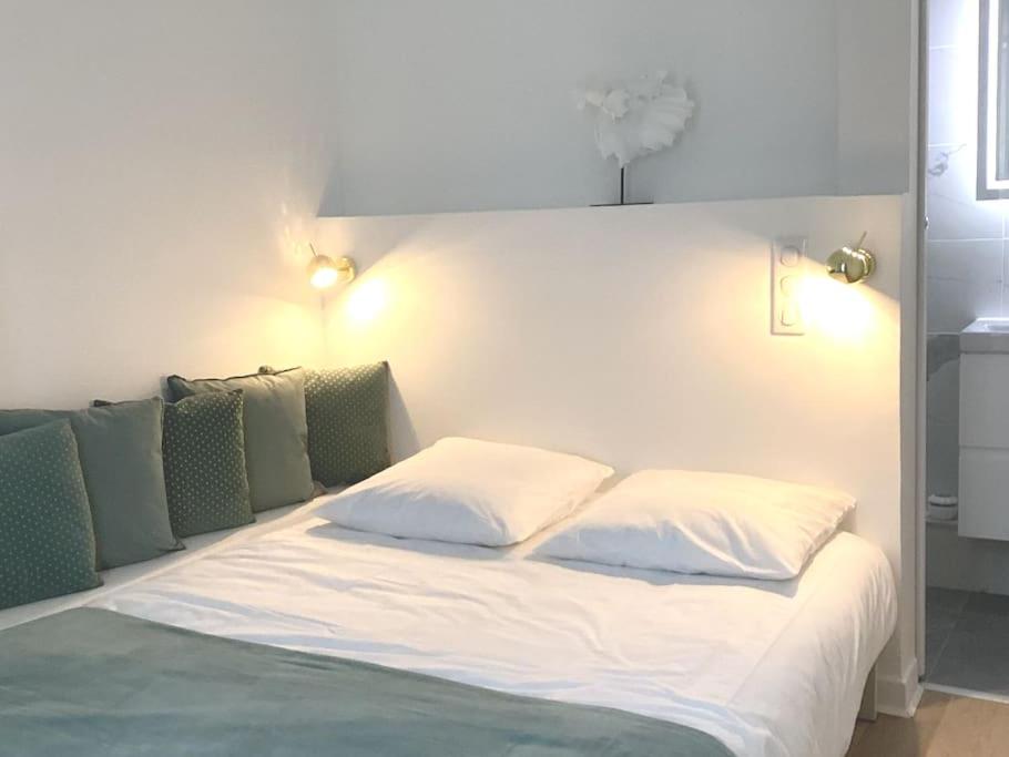 - un lit avec des draps blancs et des oreillers verts dans l'établissement Cocon chic parisien niché au cœur de Montmartre, à Paris
