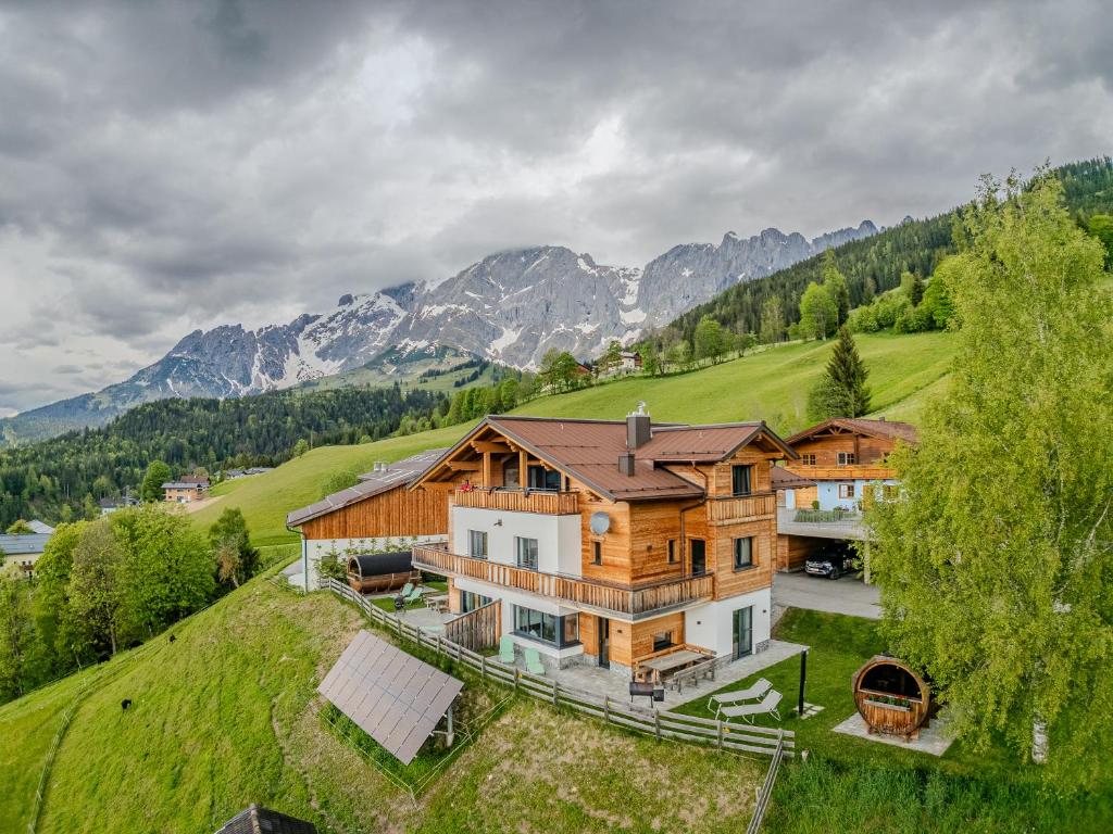 an aerial view of a house on a hill with mountains at Gut Stein Panoramalodge in Mühlbach am Hochkönig